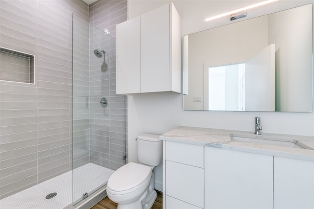 bathroom with vanity, tiled shower, wood-type flooring, and toilet