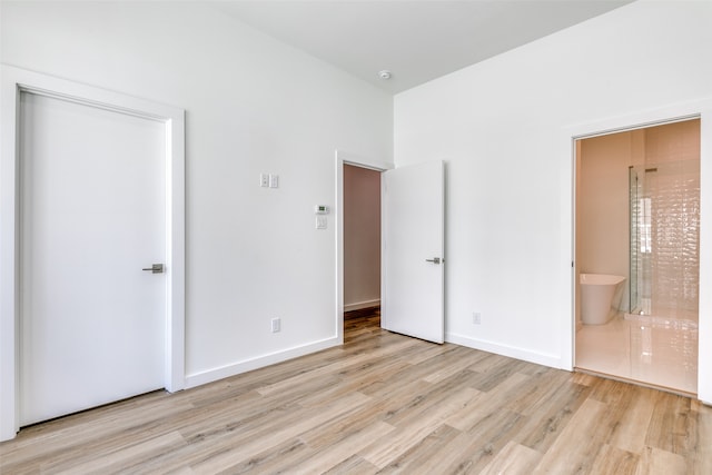 unfurnished bedroom with light hardwood / wood-style flooring and ensuite bath