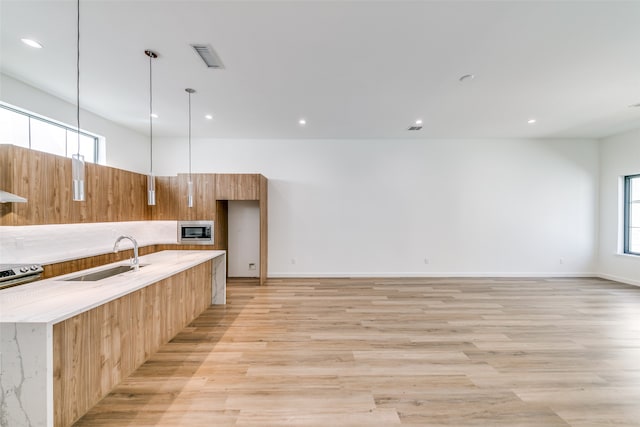 kitchen with appliances with stainless steel finishes, sink, plenty of natural light, and light wood-type flooring