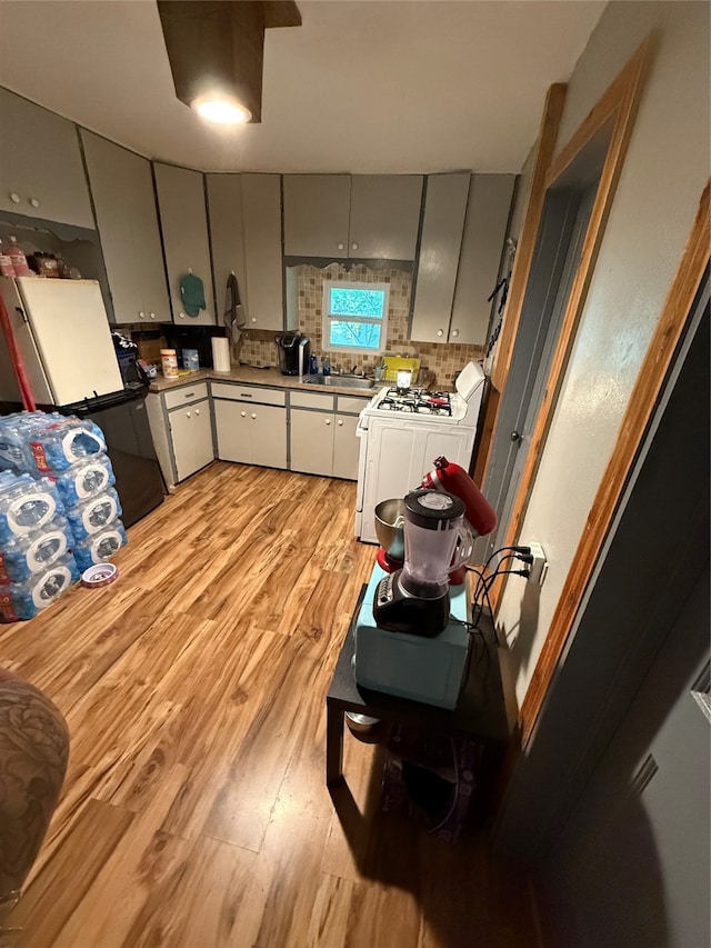 kitchen with gray cabinetry, backsplash, range, and light wood-type flooring