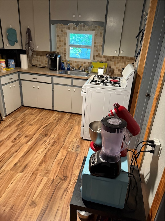 kitchen with white cabinetry, backsplash, light hardwood / wood-style flooring, and range with gas stovetop