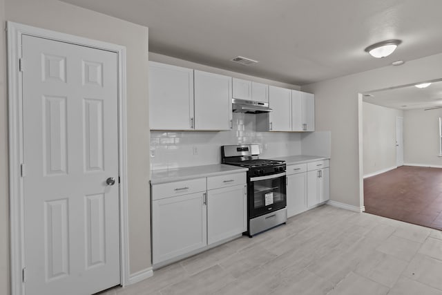 kitchen with white cabinetry, stainless steel gas range oven, and backsplash