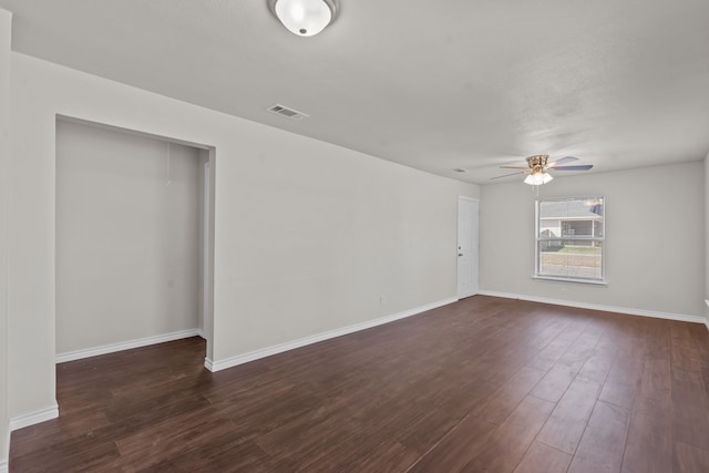 empty room with dark wood-type flooring and ceiling fan