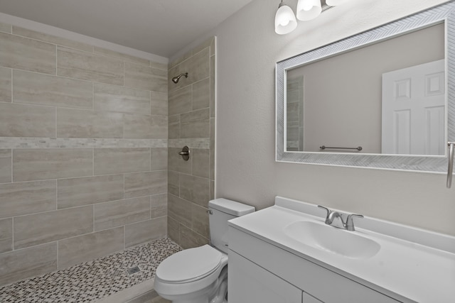 bathroom featuring vanity, tiled shower, and toilet