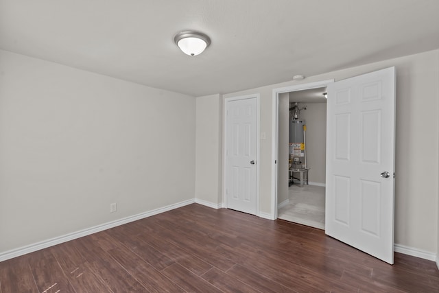 unfurnished bedroom featuring gas water heater and dark wood-type flooring