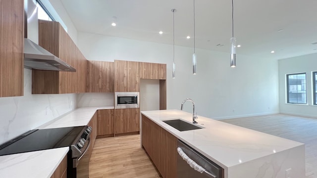 kitchen featuring a center island with sink, light wood-type flooring, sink, pendant lighting, and stainless steel appliances