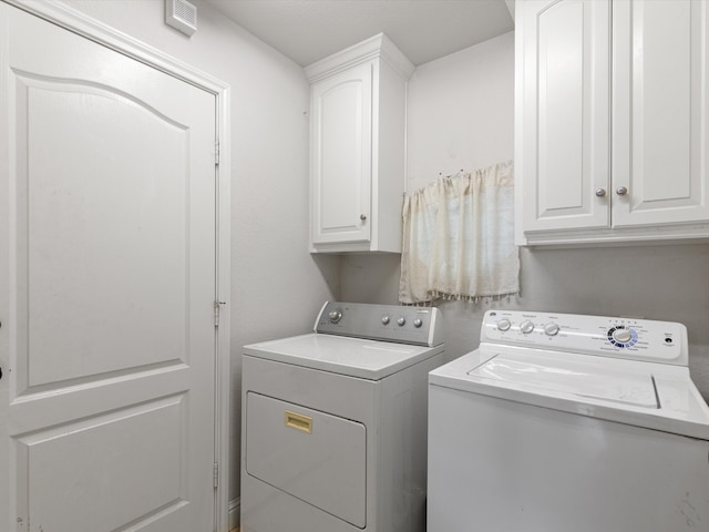 washroom featuring washer and dryer and cabinets