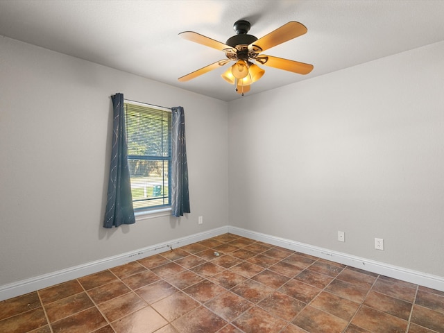 empty room with ceiling fan and dark tile patterned floors