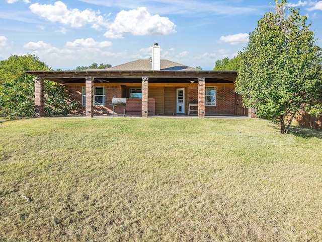 rear view of house with brick siding, a yard, and a patio
