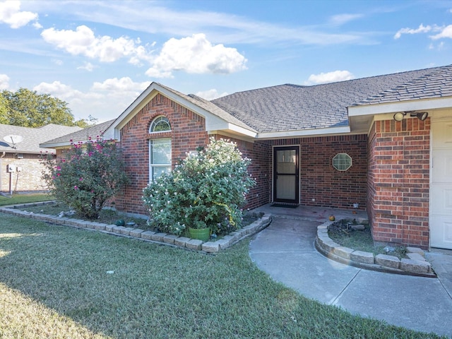 view of front of home with brick siding, a front lawn, and roof with shingles