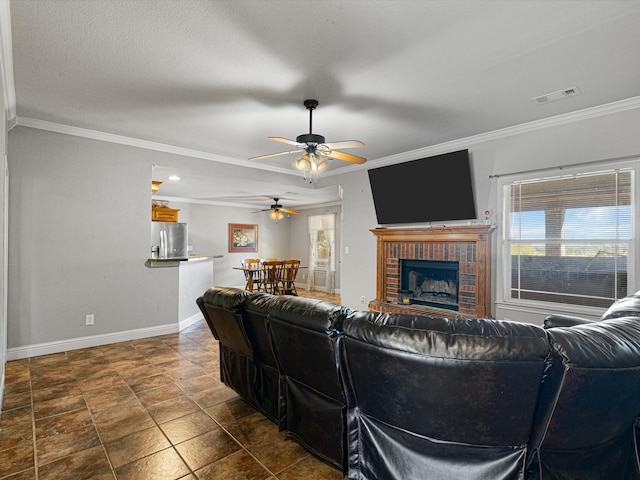 living room featuring crown molding, a textured ceiling, ceiling fan, and a brick fireplace