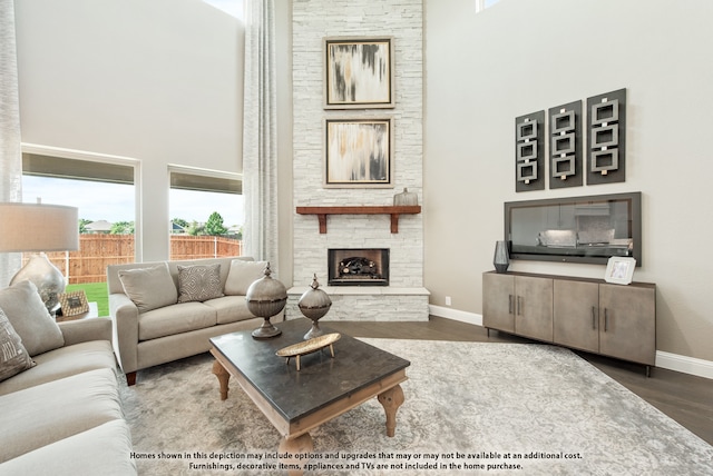 living room featuring a towering ceiling, hardwood / wood-style floors, and a stone fireplace