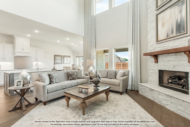 living room with a fireplace, wood-type flooring, and high vaulted ceiling