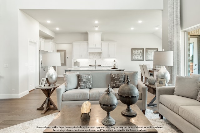 living room with vaulted ceiling, sink, and light wood-type flooring