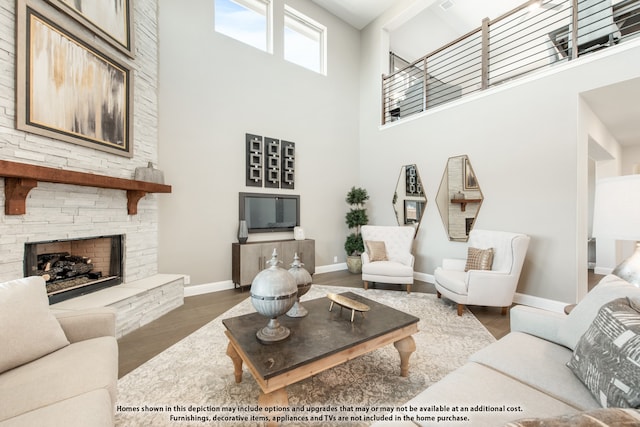 living room featuring a towering ceiling, a stone fireplace, and dark wood-type flooring