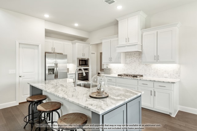 kitchen featuring white cabinetry, stainless steel appliances, and a center island with sink