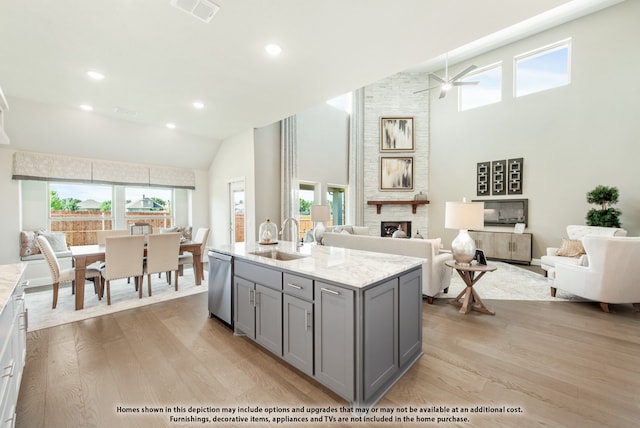 kitchen with stainless steel dishwasher, sink, light wood-type flooring, gray cabinets, and high vaulted ceiling