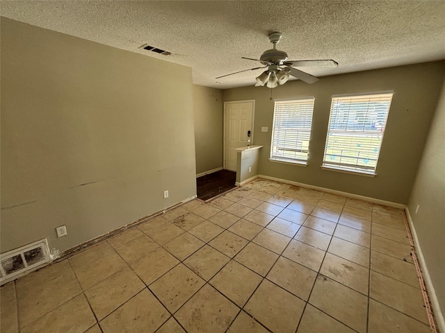 tiled empty room with a textured ceiling and ceiling fan