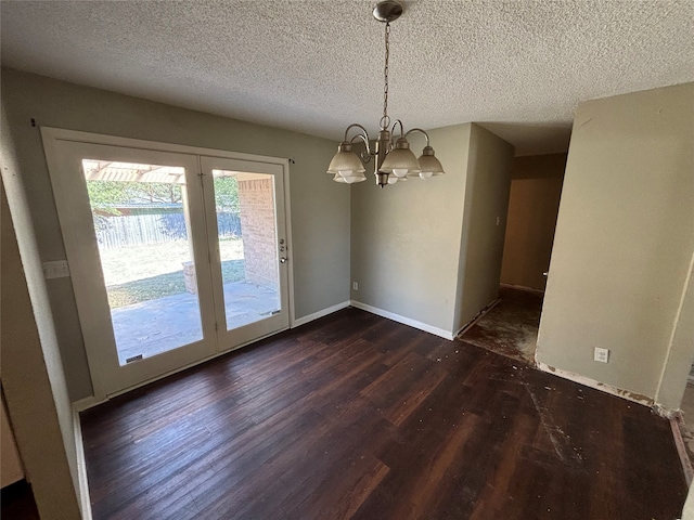 unfurnished dining area with a textured ceiling, dark hardwood / wood-style floors, and a chandelier