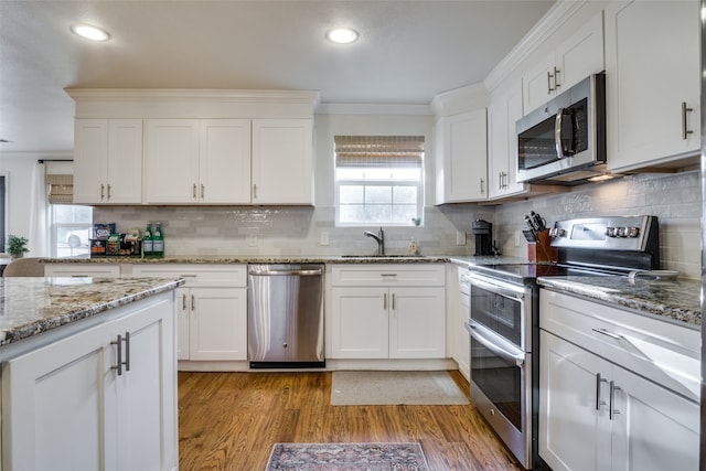 kitchen featuring stainless steel appliances, ornamental molding, sink, and white cabinets