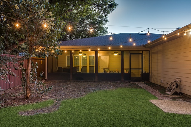 back house at dusk with a yard, ceiling fan, and a patio area