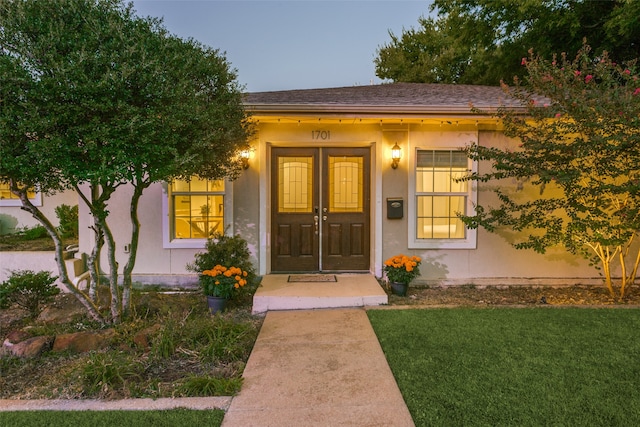 exterior entry at dusk featuring french doors and a yard