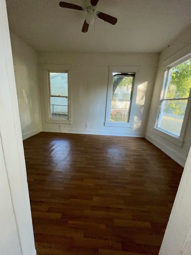 empty room with dark wood-type flooring, ceiling fan, a textured ceiling, and a wealth of natural light