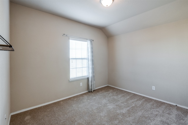 spare room featuring light carpet and vaulted ceiling