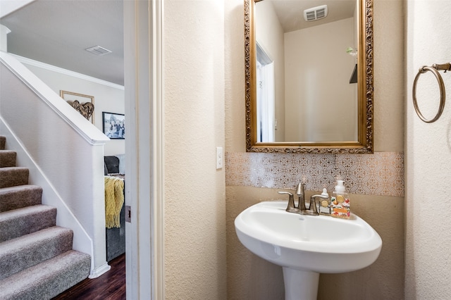 bathroom with ornamental molding, hardwood / wood-style floors, sink, and tile walls