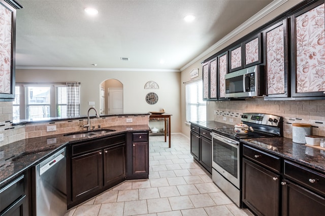 kitchen with dark stone counters, stainless steel appliances, sink, and plenty of natural light