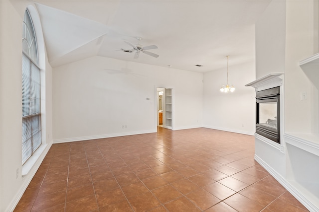 unfurnished living room with vaulted ceiling, ceiling fan with notable chandelier, and tile patterned flooring