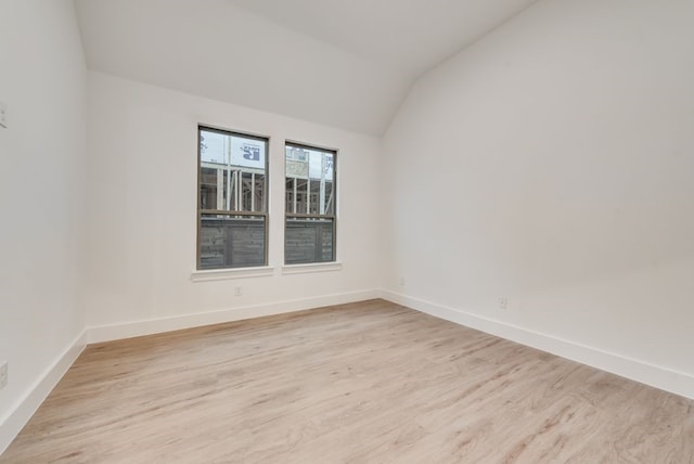 spare room featuring light hardwood / wood-style floors and lofted ceiling