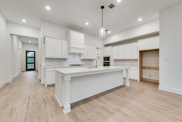 kitchen featuring white cabinetry, light hardwood / wood-style floors, appliances with stainless steel finishes, and a kitchen island with sink