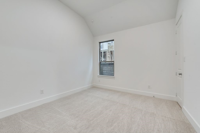 carpeted spare room featuring vaulted ceiling