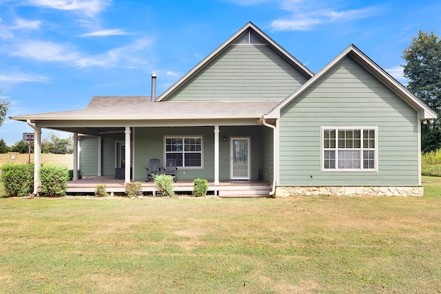 rear view of house featuring covered porch and a lawn