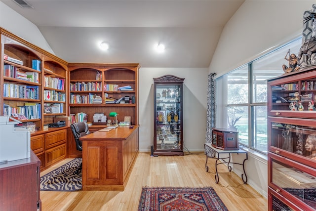 office featuring built in desk, lofted ceiling, and light hardwood / wood-style flooring