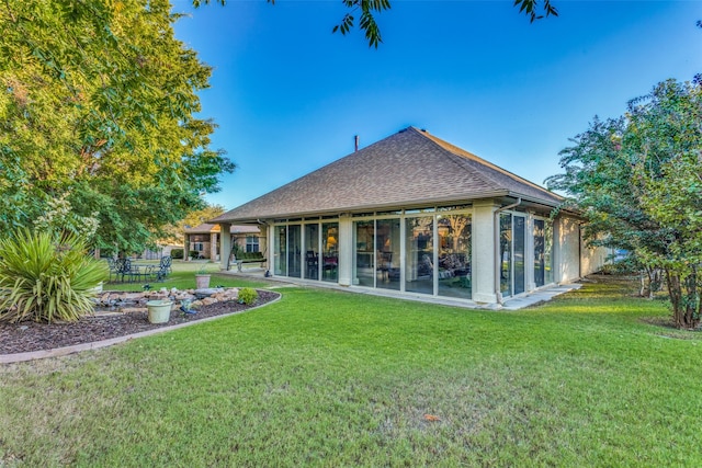 back of property with a sunroom and a lawn