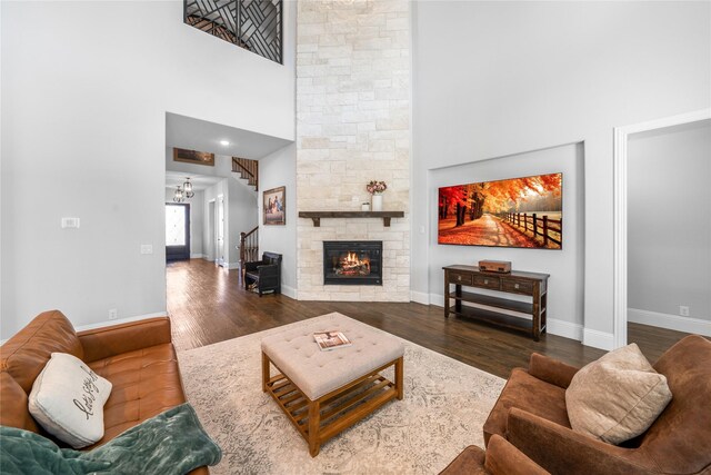 living room with a stone fireplace, hardwood / wood-style floors, and a high ceiling