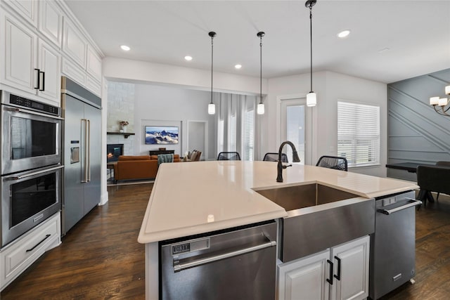 kitchen with white cabinetry, appliances with stainless steel finishes, sink, and a center island with sink