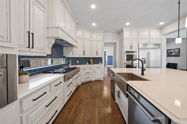 kitchen with tasteful backsplash, appliances with stainless steel finishes, dark hardwood / wood-style flooring, white cabinetry, and decorative light fixtures