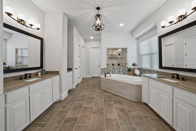 bathroom featuring vanity, a chandelier, and plus walk in shower