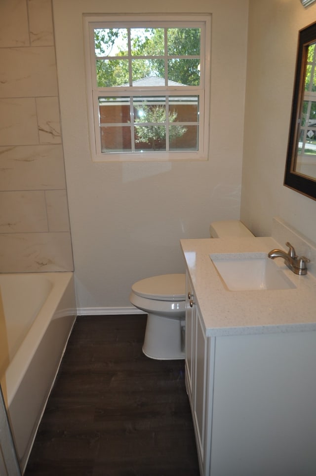 full bathroom featuring vanity, toilet, a healthy amount of sunlight, and wood-type flooring