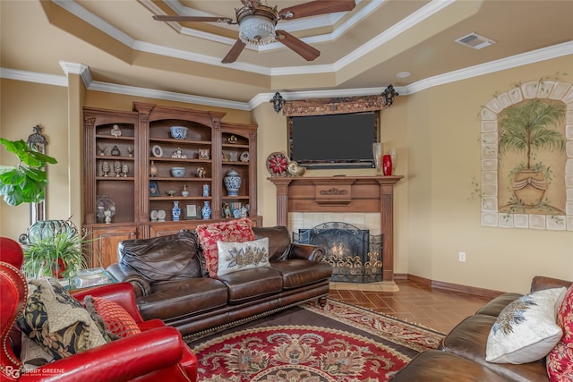 living room with a fireplace, ceiling fan, crown molding, and a tray ceiling