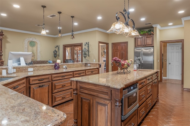 kitchen featuring decorative light fixtures, appliances with stainless steel finishes, a large island, and ornamental molding