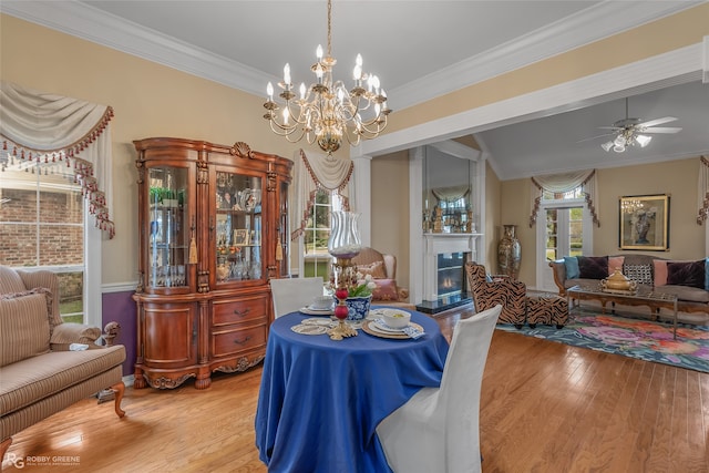 dining space featuring ornamental molding, light wood-type flooring, and ceiling fan with notable chandelier