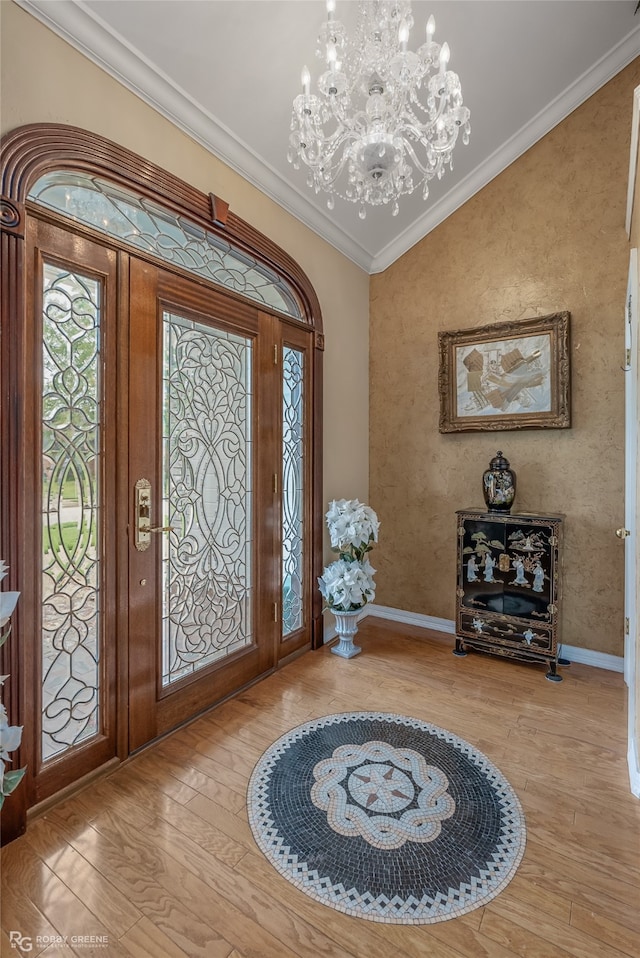 foyer entrance featuring ornamental molding, wood-type flooring, lofted ceiling, and a notable chandelier