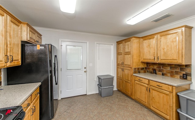 kitchen with black fridge, light countertops, stove, visible vents, and ornamental molding
