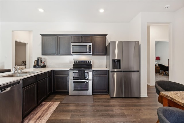 kitchen featuring sink, stainless steel appliances, dark brown cabinets, and dark hardwood / wood-style flooring