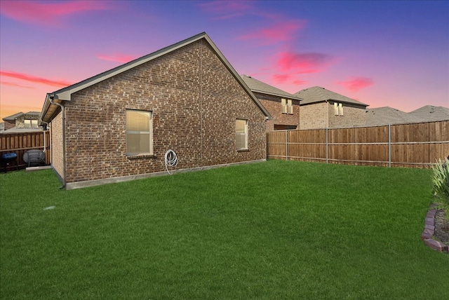 back house at dusk featuring a lawn