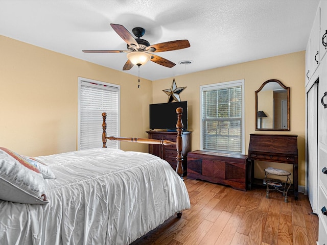 bedroom featuring ceiling fan, wood-type flooring, and a textured ceiling